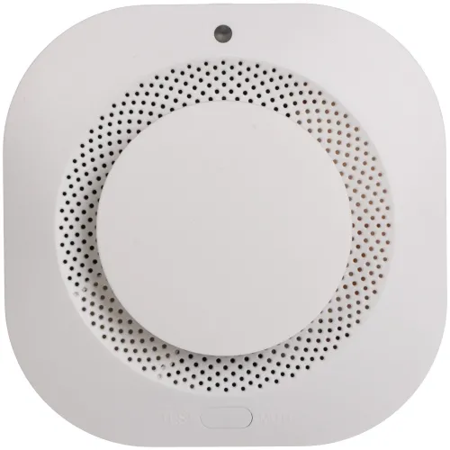 Zdjęcie przedstawia biały czujnik dymu o kwadratowym kształcie z zaokrąglonymi rogami, z centralnie umieszczonym okrągłym przyciskiem. Na dole widoczne są napisy "TEST" i "MUTE".