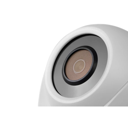 Zbliżenie na obiektyw bezprzewodowej kamery sieciowej w białej obudowie. Kamera ma nowoczesny design z wyraźnie widocznym szkłem obiektywu.