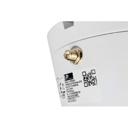 Zbliżenie na białą, bezprzewodową kamerę sieciową z widocznym złączem antenowym i etykietą z kodem QR oraz informacjami technicznymi. Kamera ma nowoczesny, minimalistyczny design.