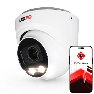 Biała kopułowa kamera IP marki Keeyo z dwoma diodami LED na froncie. Obok kamery widoczny jest smartfon z aplikacją BitVision na ekranie.