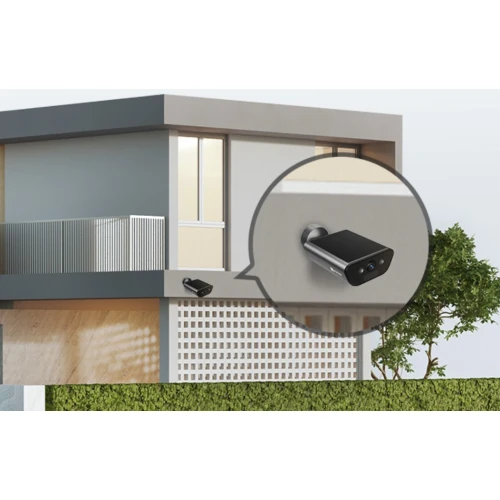 Na zdjęciu widoczny jest nowoczesny budynek z zamontowaną na zewnętrznej ścianie kamerą smart home. Kamera jest pokazana w powiększeniu, co podkreśla jej elegancki, czarny design.