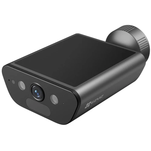 Na zdjęciu znajduje się czarna, nowoczesna kamera smart home z obiektywem i czujnikami na przednim panelu. Kamera ma kompaktowy, prostokątny kształt z zaokrąglonymi krawędziami i jest zasilana bateriami.