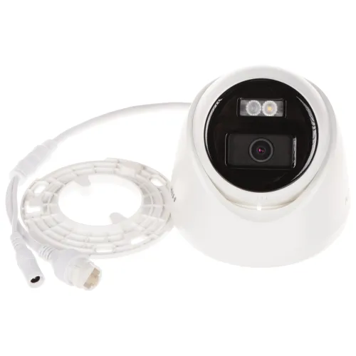 Na zdjęciu znajduje się biała kamera monitoringu z wyjętym pierścieniem zaciskowym, ukazująca obiektyw i diody LED. Obok kamery leży odłączony pierścień oraz kabel z wtyczką.