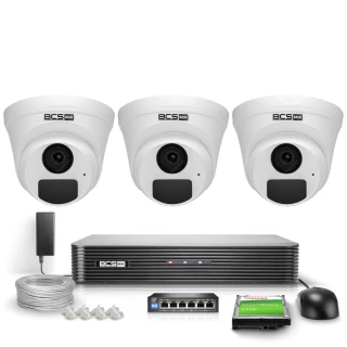 Na zdjęciu znajduje się zestaw monitoringu IP BCS Basic, składający się z trzech kamer kopułkowych, rejestratora, kabla, zasilacza, switcha oraz dysku twardego. Wszystkie elementy są ułożone na białym tle, prezentując kompletny system do nadzoru wizyjnego.