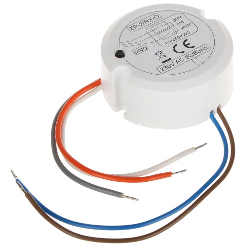 Na zdjęciu znajduje się okrągły odbiornik systemu bezprzewodowego ZP-2RX-O w białej obudowie z wystającymi przewodami w różnych kolorach. Na górnej części obudowy widoczna jest etykieta z informacjami technicznymi, w tym napięciem 230V AC 50/60Hz.