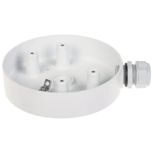 Na zdjęciu znajduje się okrągła, biała puszka montażowa z trzema podwyższonymi punktami mocowania i metalowym uchwytem wewnątrz. Po prawej stronie widoczny jest plastikowy dławik kablowy.