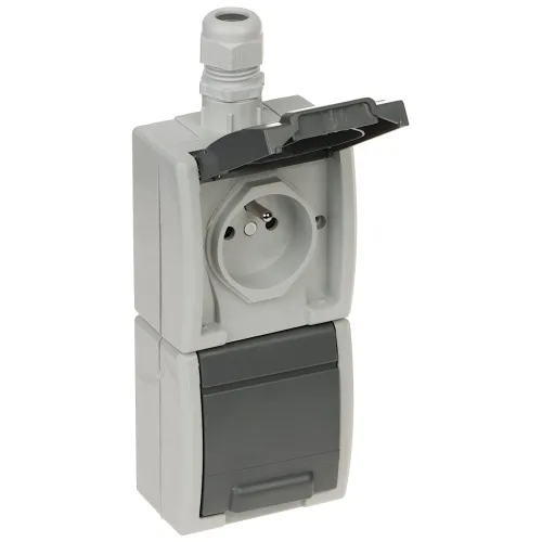 Na zdjęciu znajduje się szara, podwójna gniazdko elektryczne z klapką ochronną, zamontowane w pionie. Górna część gniazdka jest otwarta, ukazując okrągłe wejście na wtyczkę.