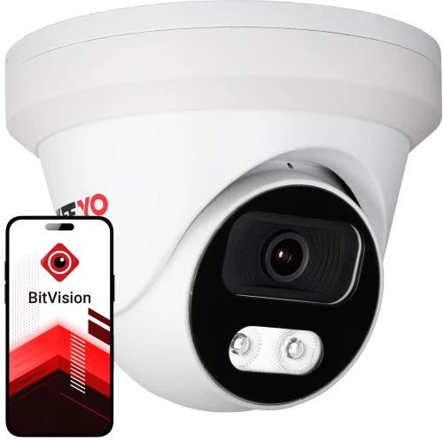 Na zdjęciu znajduje się biała kamera monitoringu o nowoczesnym designie, obok której widoczny jest smartfon z aplikacją BitVision na ekranie. Kamera ma czarny panel z obiektywem i diodami LED.